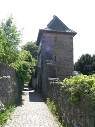 Trinsenturm in Ratingen Ein historischer Steinturm flankiert von einer verwinkelten, mit Kopfsteinpflaster bedeckten Gasse.