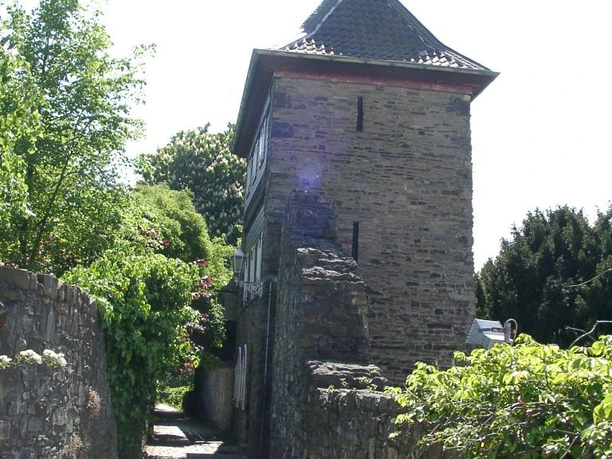 Trinsenturm in Ratingen Ein historischer Steinturm flankiert von einer verwinkelten, mit Kopfsteinpflaster bedeckten Gasse.