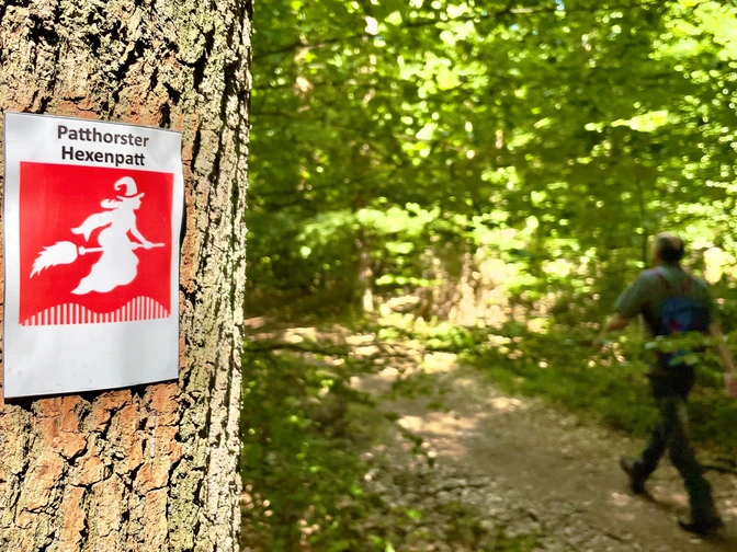 Ein Schild mit einer Hexe auf einem Besen kennzeichnet den grünen Waldweg im Patthorster Hexenpatt.