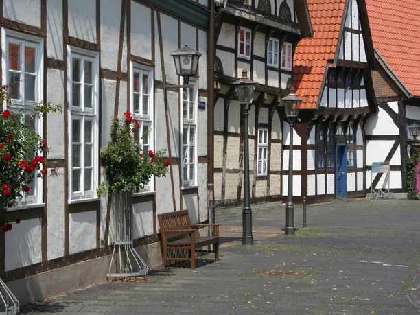 Half-timbered houses in Nienburg with red roof tiles, decorated with flowers and historic street lamps.