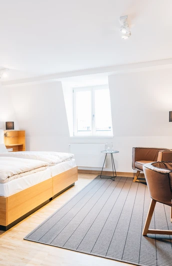 Helles, modernes Hotelzimmer mit Doppelbett, Schreibtisch, Stuhl und Wandfernseher in stilvollem Design.