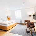 Liborianum, Zimmer Helles, modernes Hotelzimmer mit Doppelbett, Schreibtisch, Stuhl und Wandfernseher in stilvollem Design.