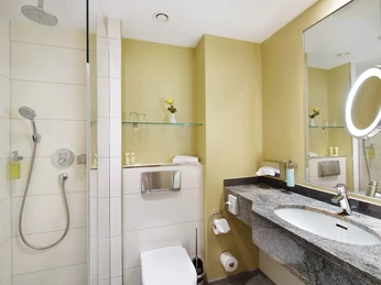 Modernes Duschbad mit barrierefreier Regendusche und stylischem Waschtisch im Hotelzimmer.