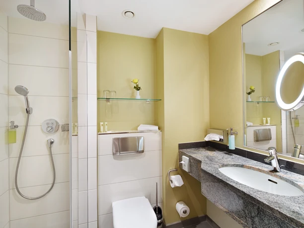 Modernes Duschbad mit barrierefreier Regendusche und stylischem Waschtisch im Hotelzimmer.