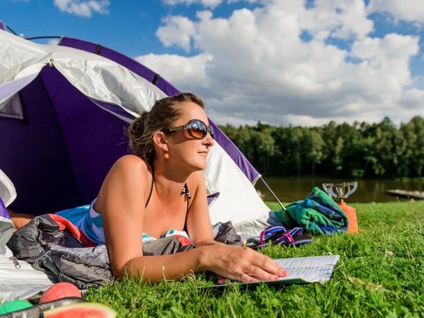 Thümmlitzsee in Grimma - Camping in der Leipzig Region Eine Frau liegt in einem Zelt und ließt eine Broschüre, Camping in Leipzig, Urlaub