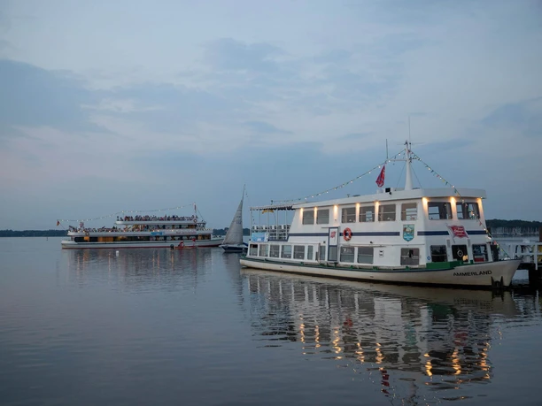 Weisse-Flotte-Abendfahrt-Zwischenahner-Meer.jpg Die beleuchtete Weisse Flotte legt am Abend am ruhigen Zwischenahner Meer an, während ein weiteres Schiff in der Ferne kreuzt.