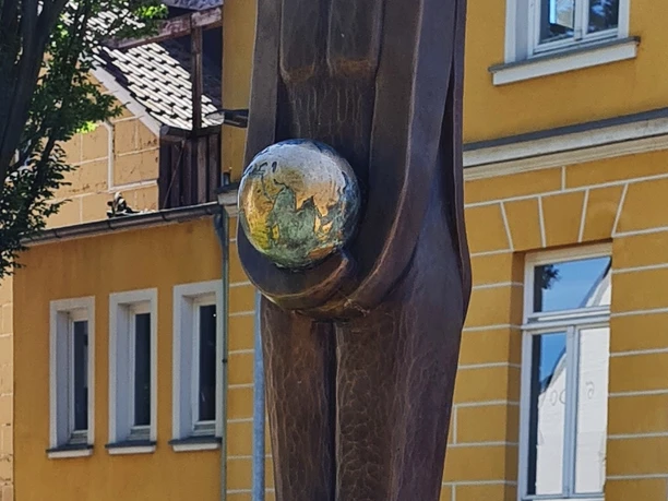 Bronzestatue in Vlotho, die eine stehende Figur mit einem Erdball in den Händen darstellt.