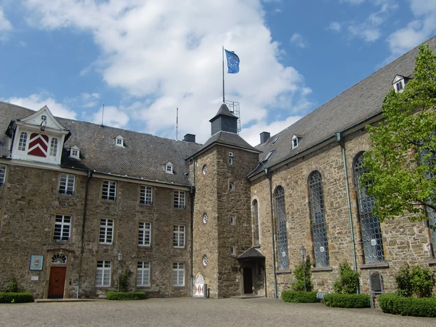 Schloss Hückeswagen Schloss Hückeswagen mit historischem Mauerwerk und Turm unter blauem Himmel, umgeben von Bäumen.