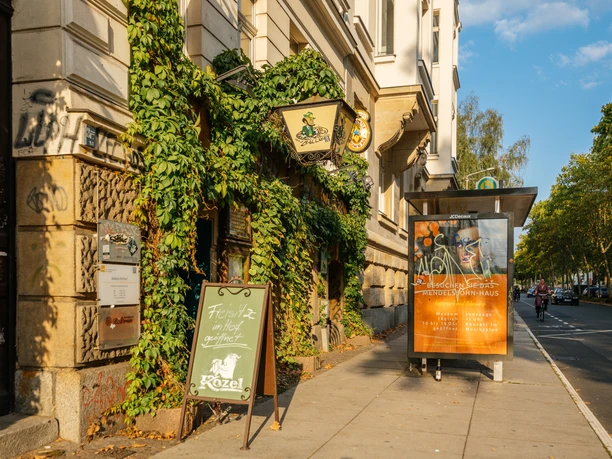 Noels Ballroom - Kneipen & Pubs in Leipzig Außenansicht des Noels Ballrooms und seine bewachsene Fassade, mit Schild und Straße im Hintergrund bei Sonnenschein