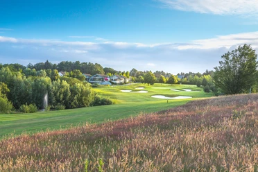 Golfclub Hösel in Heiligenhaus Golfplatz mit gepflegtem Grün und Bunkern, umgeben von Bäumen und einem Clubhaus im Hintergrund.