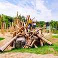 Steinzeitspielplatz am Neanderthal Museum in Mettmann Kinder spielen auf einem aus Holzstämmen gestalteten Abenteuer-Spielgerät im Freien.