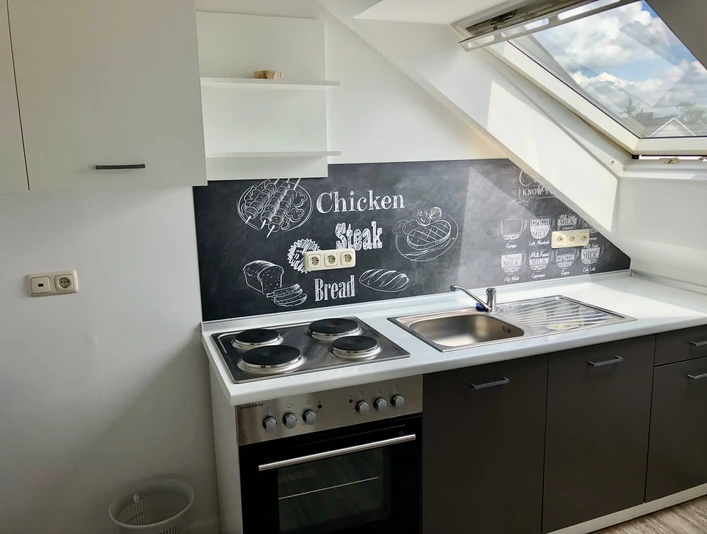 Moderne Küchenzeile mit Dachfenster und Kreidetafel-Dekor. Helle, freundliche Einrichtung.
