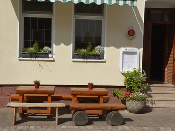 Gasthof zum Herzog Zwei rustikale Holzbänke und Tische vor einem Gasthofeingang mit Blumenschmuck und Markise.