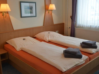 Gasthof zum Herzog Ein Doppelzimmer mit zwei Einzelbetten, frischen Handtüchern, warmer Beleuchtung und Tageslicht.