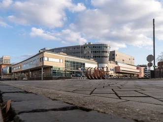 CityPalais mit Casino, Duisburg Das CityPalais in Duisburg zeigt eine moderne Architektur mit Glasfassaden und integriertem Casino, umgeben von einem weitläufigen Platz und unter einem bewölkten Himmel.