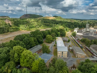 Industrial site on the green Piesberg, Osnabrück, with wind turbines and historic architecture.