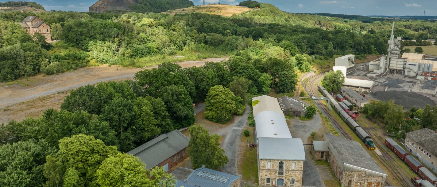 Industrial site on the green Piesberg, Osnabrück, with wind turbines and historic architecture.