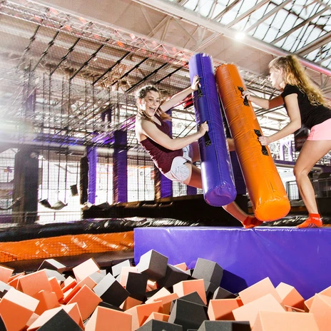Dwie dziewczęta rywalizują na torze przeszkód w parku trampolin Jump House