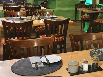 Alt-Enginger Mühle: Restaurant à la carte Ein einladendes Restaurant mit rustikalen Holzmöbeln und liebevoll gedeckten Tischen in warmem Licht.