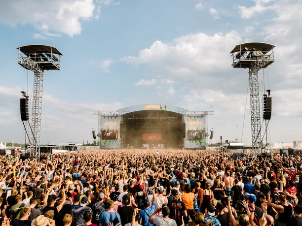 Many people stand in front of the Highfield's big stage and celebrate exuberantly, festival in Leipzig, city of music