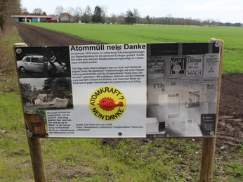Infotafel zur Anti-Atomkraftbewegung mit historischen Informationen und Protestbildern auf einem Feld.