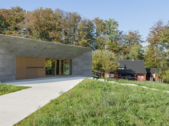 Museum Peter August Böckstiegel Modernes, graues Gebäude in natürlicher Umgebung, daneben ein traditionelles rotes Haus im Grünen.