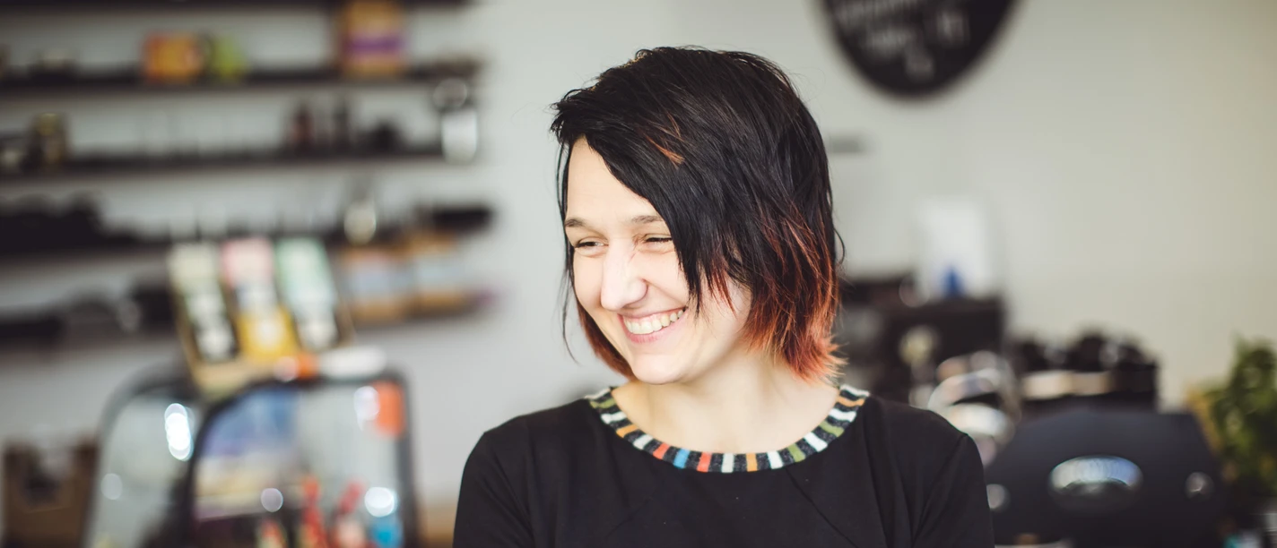 Simona stojí s kávou před svým pultem a usmívá se, kavárna a restaurace v Lipsku