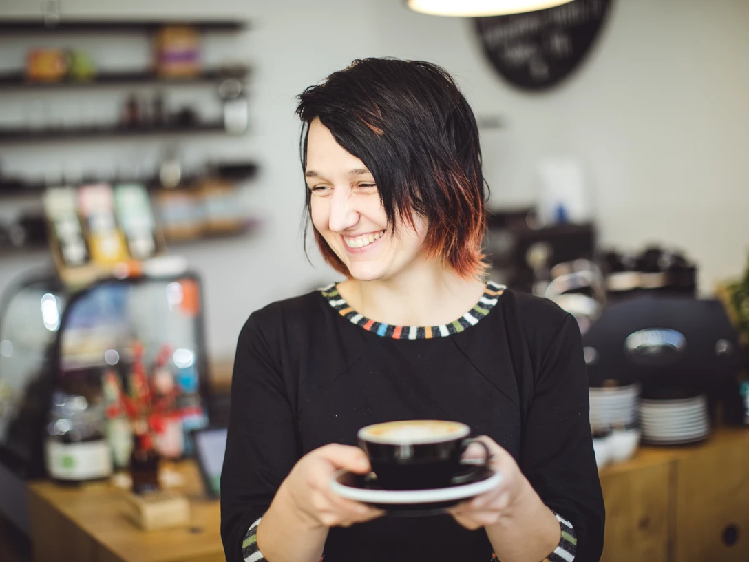 7Shots-Coffee-Simona-Gastro-Kaffee-Leipzig-travel.jpg Simona steht mit einem Kaffee vor ihrer Theke und Lächelt, Café, Gastros in Leipzig