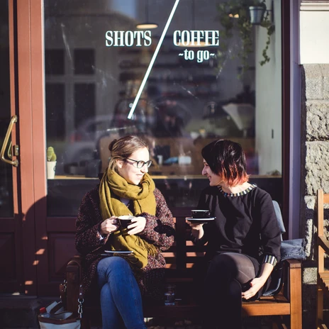 Two women chatting on a bench while drinking coffee, Café in Leipzig, Gastro