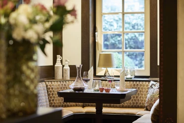 Elegante, gemütliche Restaurant-Ecke mit Holzverkleidung, gedecktem Tisch und Fenster mit Ausblick.