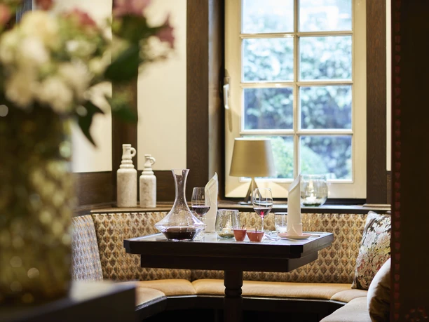 Elegante, gemütliche Restaurant-Ecke mit Holzverkleidung, gedecktem Tisch und Fenster mit Ausblick.