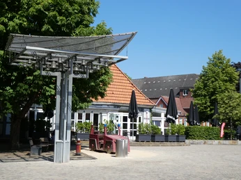 Alte Feuerwache und Glockenspiel Feuerwache mit markantem Glockenspiel im Vordergrund, umgeben von Bäumen und blauem Himmel.