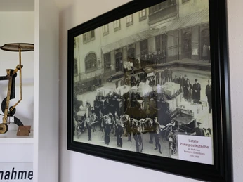 Postmuseum Bokel Das Bild zeigt ein gerahmtes historisches Foto im Postmuseum Bokel, mit der Aufschrift „Letzte Paketpostkutsche“ und verschiedenen Exponaten im Vordergrund. Die Ausstellung vermittelt einen Eindruck von der Geschichte der Postzustellung.