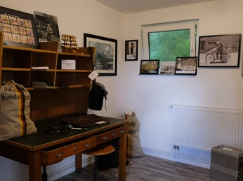 Postmuseum Bokel Drinnen im Postmuseum Bokel: Ein historischer Schreibtisch voller Vintage-Postutensilien, umgeben von Schwarz-Weiß-Fotografien.