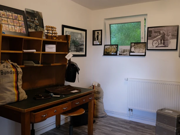 Postmuseum Bokel Drinnen im Postmuseum Bokel: Ein historischer Schreibtisch voller Vintage-Postutensilien, umgeben von Schwarz-Weiß-Fotografien.