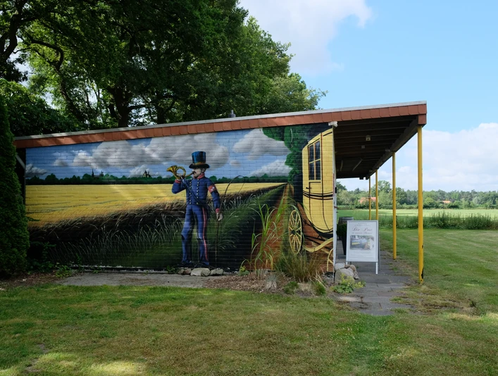 Postmuseum Bokel Das Gebäude des Postmuseums in Bokel mit einer großen Wandmalerei eines Postboten und einer Kutsche.