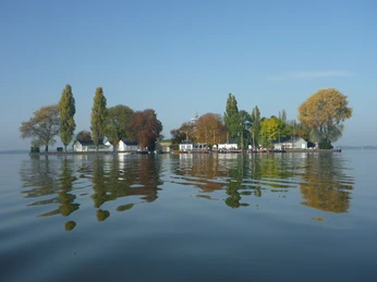 Im klaren Wasser spiegeln sich herbstliche Bäume und historische Gebäude der Insel Wilhelmstein.Autumnal trees and historic buildings on the island of Wilhelmstein are reflected in the clear water.Det klare vand reflekterer efterårstræer og historiske bygninger på øen Wilhelmstein.Het heldere water weerspiegelt de herfstachtige bomen en historische gebouwen op het eiland Wilhelmstein.