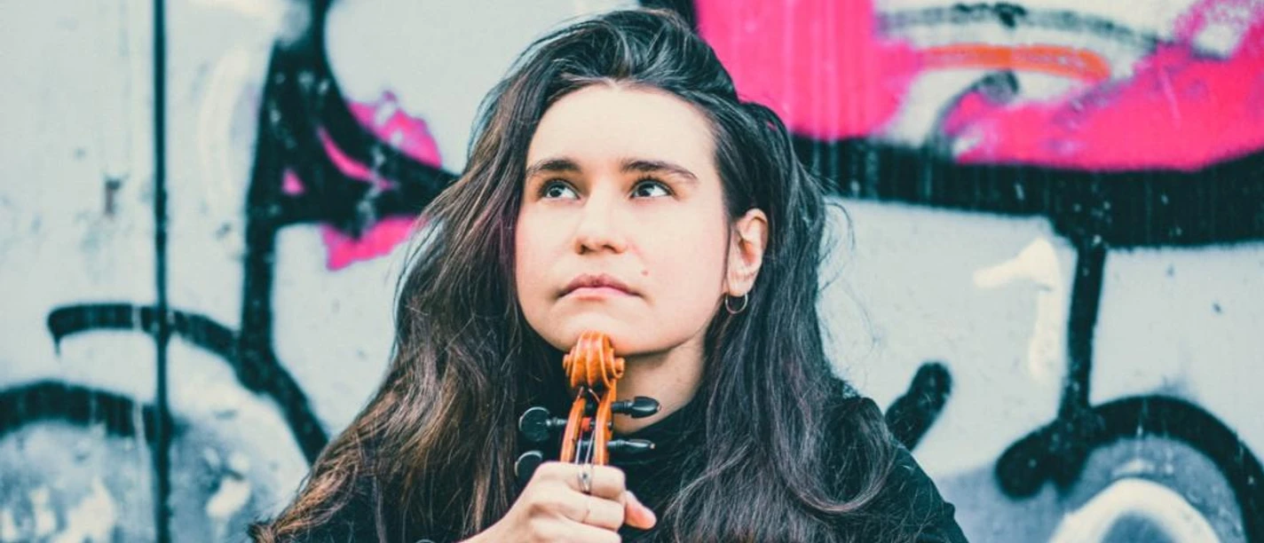 Izabela-Kałduńska-Violinistin-Kultur-Musik-Liamera-Photography-Leipzig-Travel.jpg Izabela-Kałduńska sitzt mit ihrer Violine vor einer Mauer, die mit Grafiti besprüht ist, Musikstadt Leipzig, Kultur