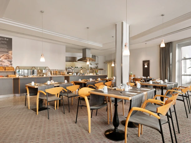 Helles Frühstücksrestaurant mit Holztischen, modernem Buffetbereich und großen Fenstern im Ramada Bottrop