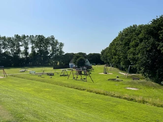 Kinderspielplatz am Deich Spielplatz auf großer Wiese neben Bäumen am Deich