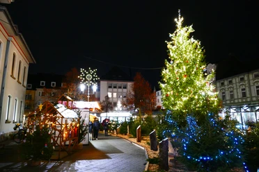 Aufblick-auf-den-Weihnachtsmarkt-Heiligenhaus-mit-Weihnachtsbaum.JPG Ein festlich beleuchteter Weihnachtsbaum auf einem stimmungsvollen Markt im nächtlichen Heiligenhaus.