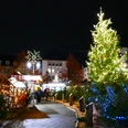 Aufblick-auf-den-Weihnachtsmarkt-Heiligenhaus-mit-Weihnachtsbaum.JPG Ein festlich beleuchteter Weihnachtsbaum auf einem stimmungsvollen Markt im nächtlichen Heiligenhaus.