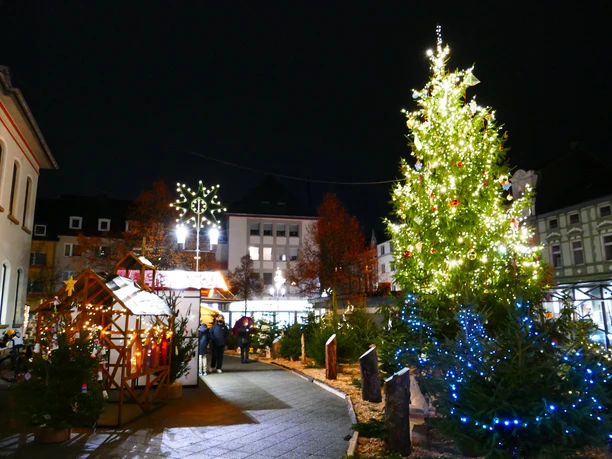 Aufblick-auf-den-Weihnachtsmarkt-Heiligenhaus-mit-Weihnachtsbaum.JPG Ein festlich beleuchteter Weihnachtsbaum auf einem stimmungsvollen Markt im nächtlichen Heiligenhaus.