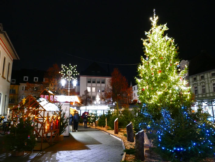 Aufblick-auf-den-Weihnachtsmarkt-Heiligenhaus-mit-Weihnachtsbaum.JPG Ein festlich beleuchteter Weihnachtsbaum auf einem stimmungsvollen Markt im nächtlichen Heiligenhaus.
