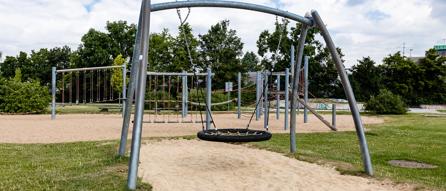 Spielplatz Am Sandbach in Ratingen Ein moderner Spielplatz mit Klettergerüsten und Schaukeln, umgeben von grünen Bäumen und Wiesen.