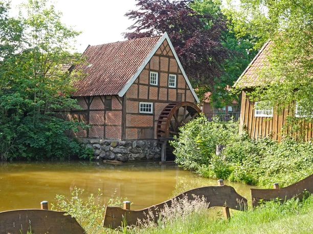 Wassermühle Bruneforth in Stavern ©Emsland Tourismus GmbH (4).JPG Fachwerk-Wassermühle mit großem Holzwasserrad an einem Teich, umgeben von dichtem Grün und Bäumen.