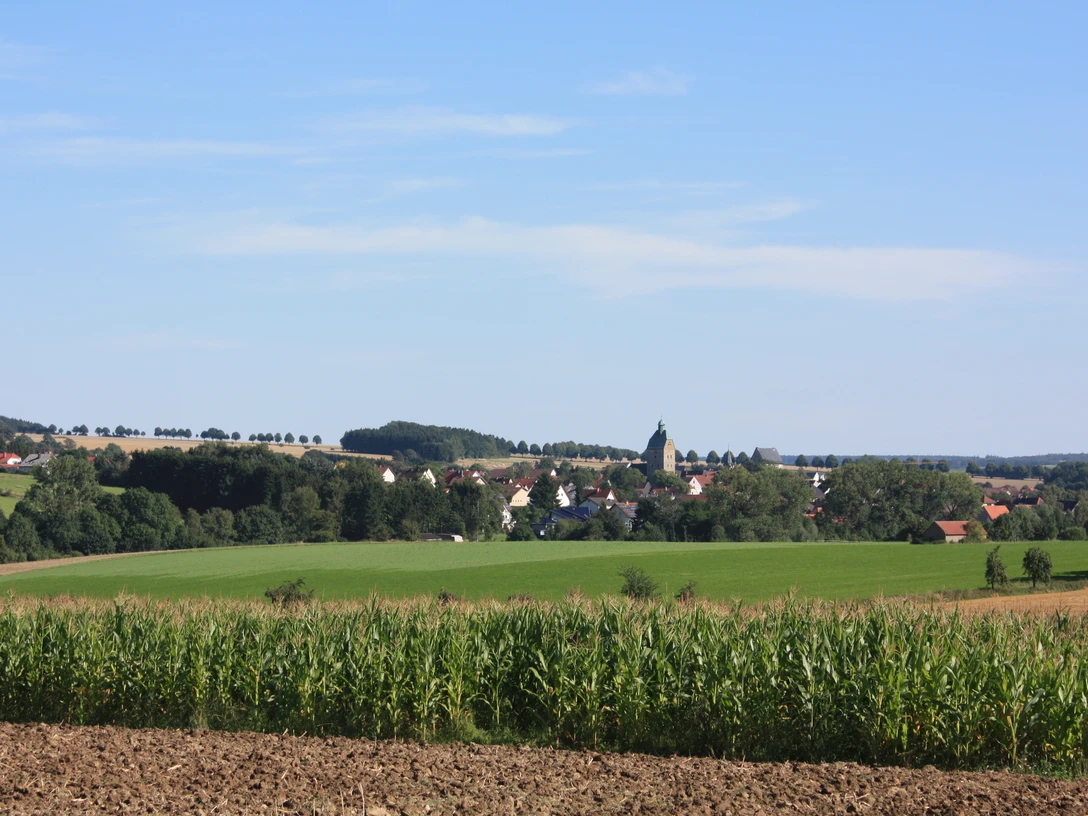 Lichtenau | Ortsansicht Blick auf das Dorf Lichtenau, eingebettet in grüne Felder und umgeben von sanften Hügeln.