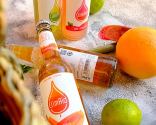 ClimAid Limonaden aus Haan ClimAid Limonadenflaschen liegen vor verschiedenen Zitrusfrüchten und versprechen erfrischenden Genuss.