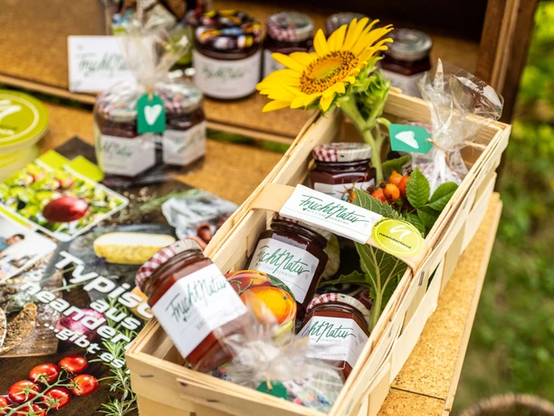 FruchtNatur Aufstriche aus Langenfeld Ein Tisch mit verschiedenen Fruchtaufstrichen von FruchtNatur und einer Sonnenblume in einem Korb.