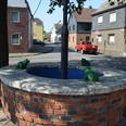 Kradepohl in Monheim am Rhein Ein runder Brunnen aus Ziegelsteinen mit Froschfiguren steht an einer Straßenkreuzung in Monheim am Rhein.